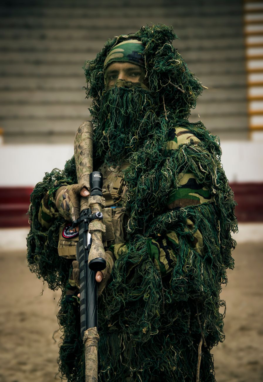 camouflaged soldier with sniper rifle in urban setting